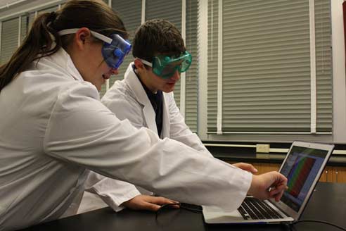 Students with goggles on pointing at a laptop