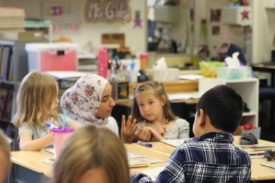 A student teacher helps children in a local classroom