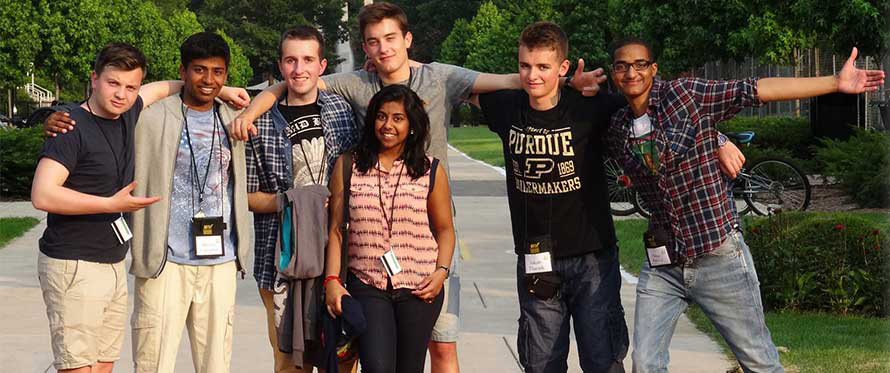 Seven BFTF students posing for a picture outside. They are huddled together with their arms around each other's shoulders.