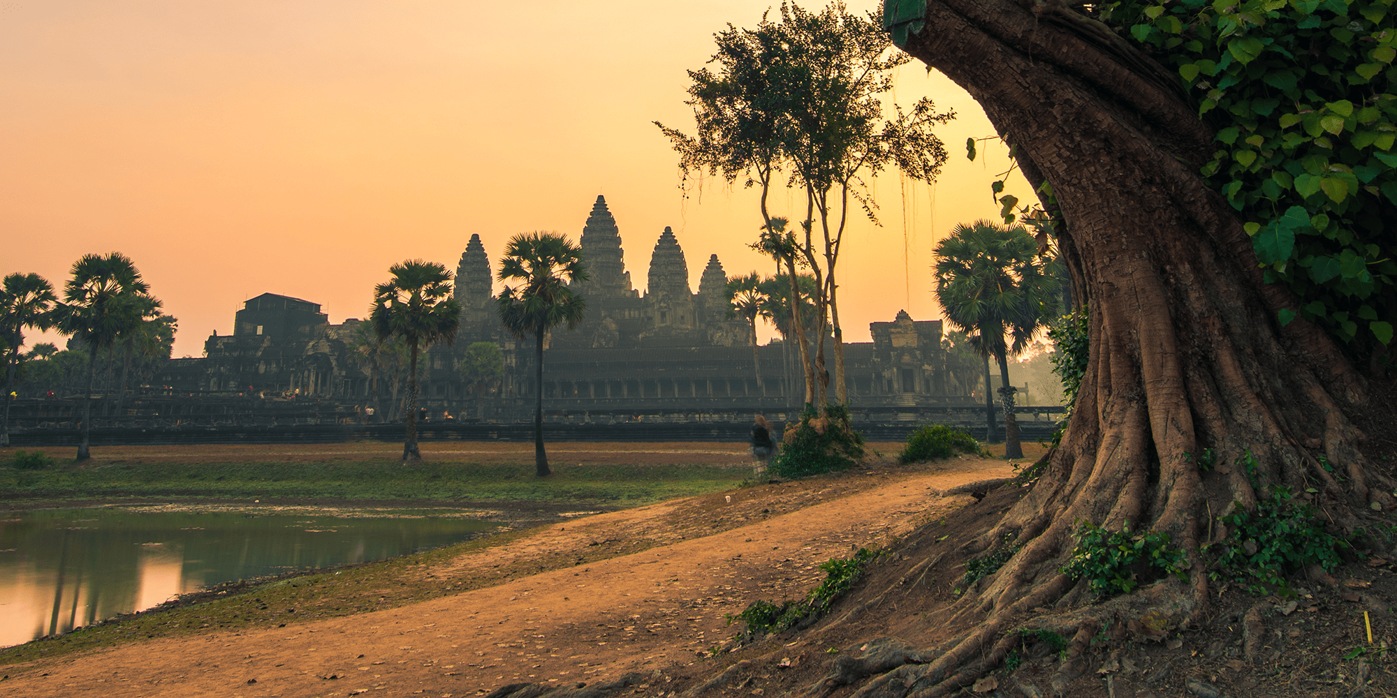 A sunset in Cambodia featuring the Angkor Wat in the background.