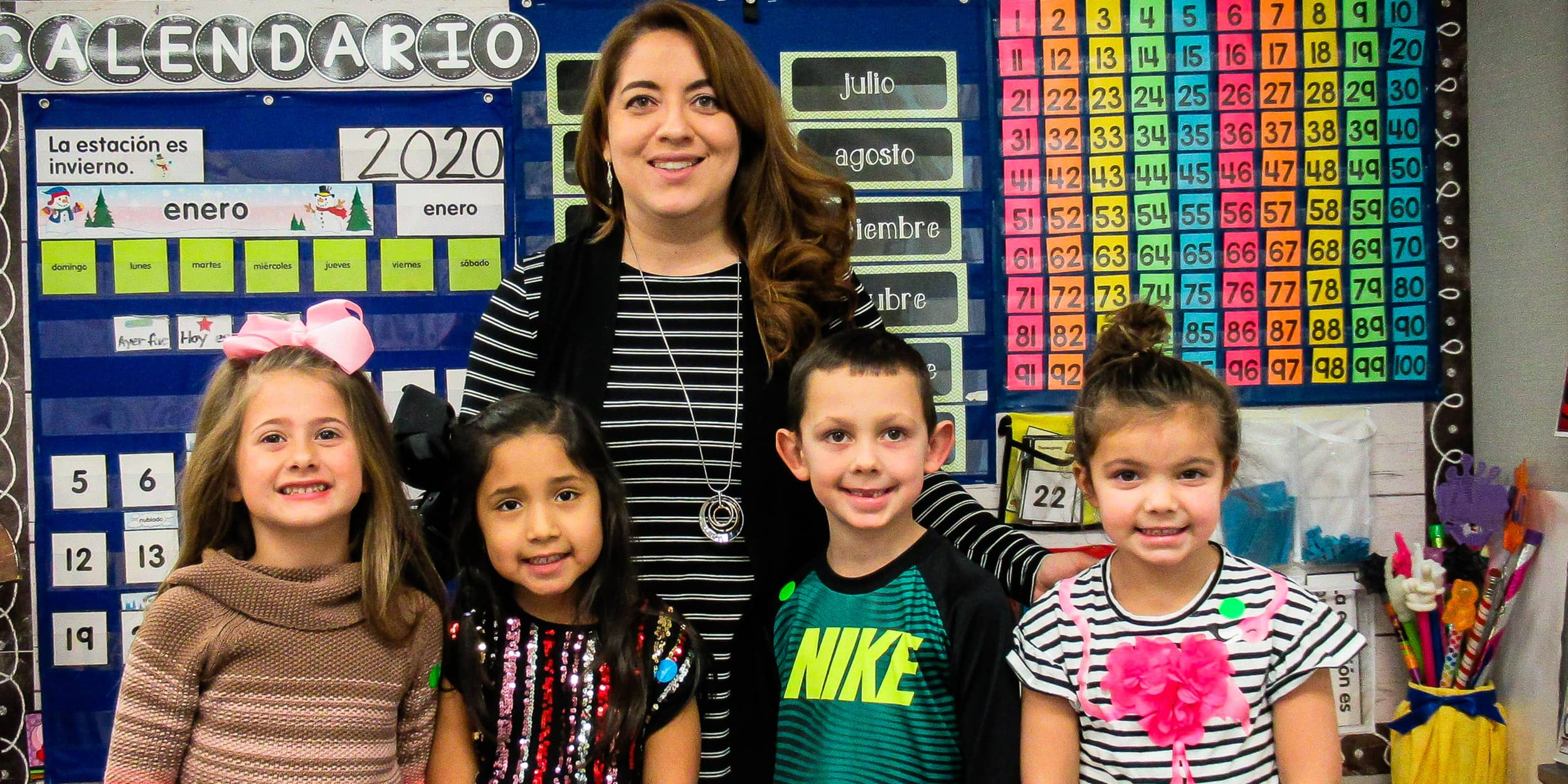 A female teacher with a group of students in front of a classroom