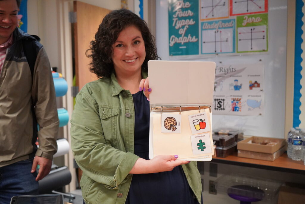 A faculty member holds up an instructional material at the grand opening of CREATE