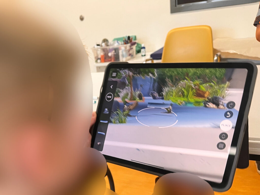 Over-the-shoulder view of a child exploring a wetland using an augmented reality application on an iPad