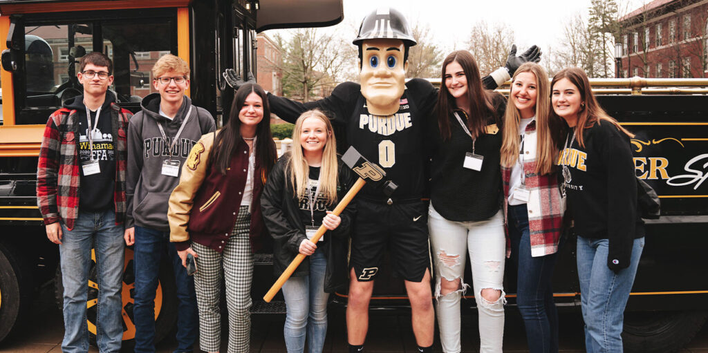 Purdue Pete with students in front of Boilermaker Special.