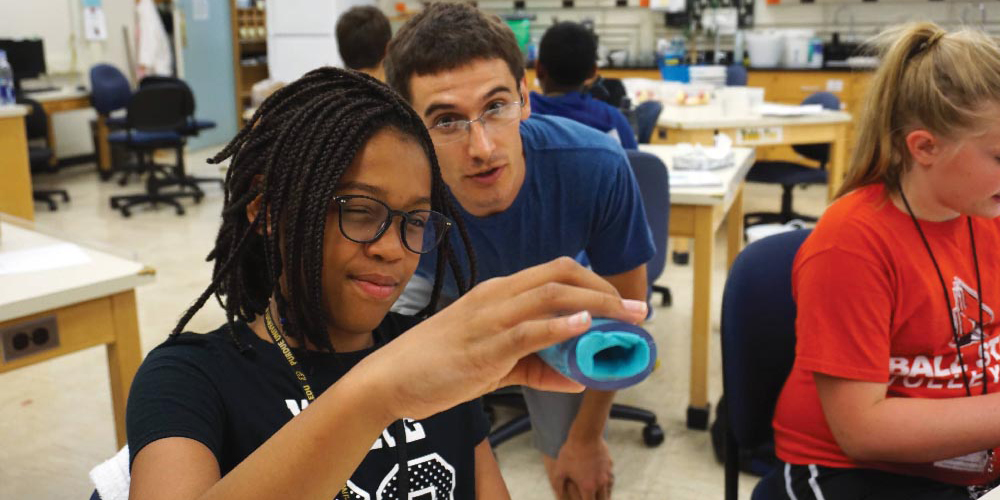 Student teacher with middle school student conducting a science experiment.