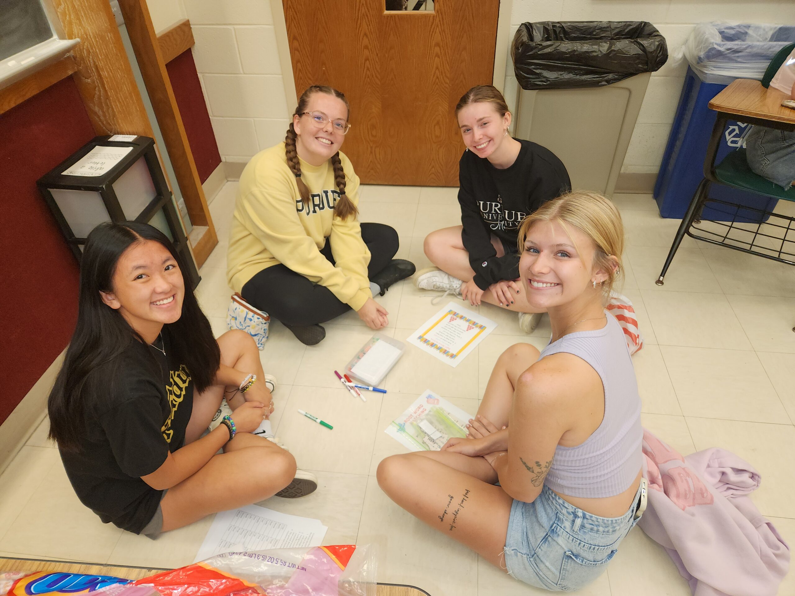 A group of students sit on the floor working on an activity