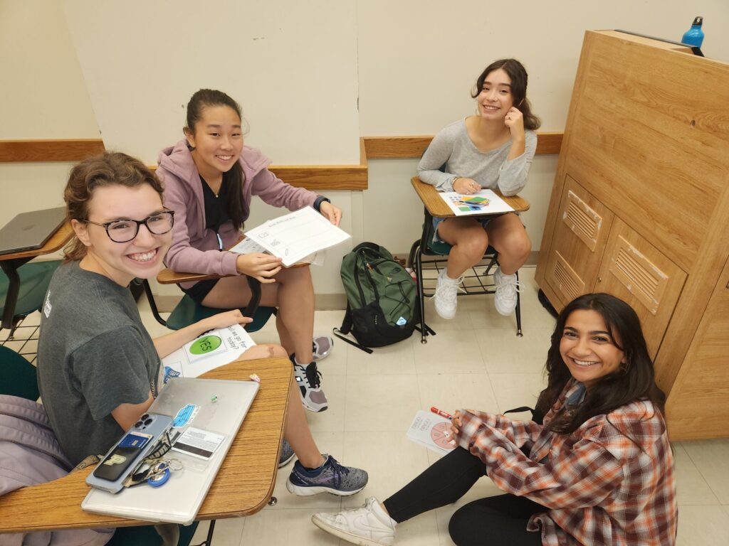 A group of students sit in a circle working together