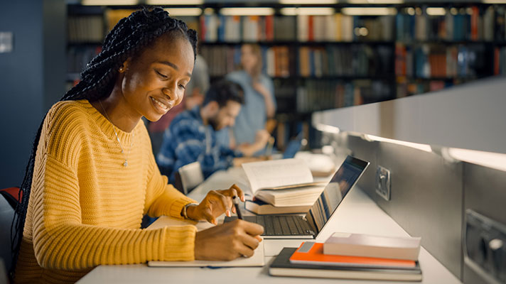 A black female works on a laptop in a library