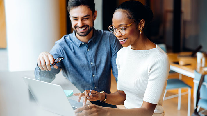 Two colleagues work together on a laptop