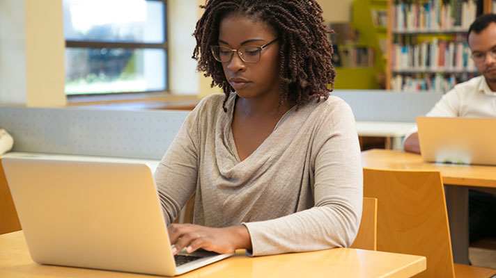 A black female works on a laptop in a library
