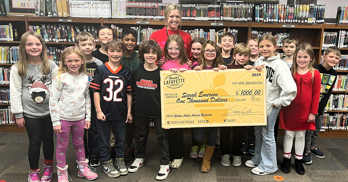 Teacher and her students holding a large yellow Golden Apple check.