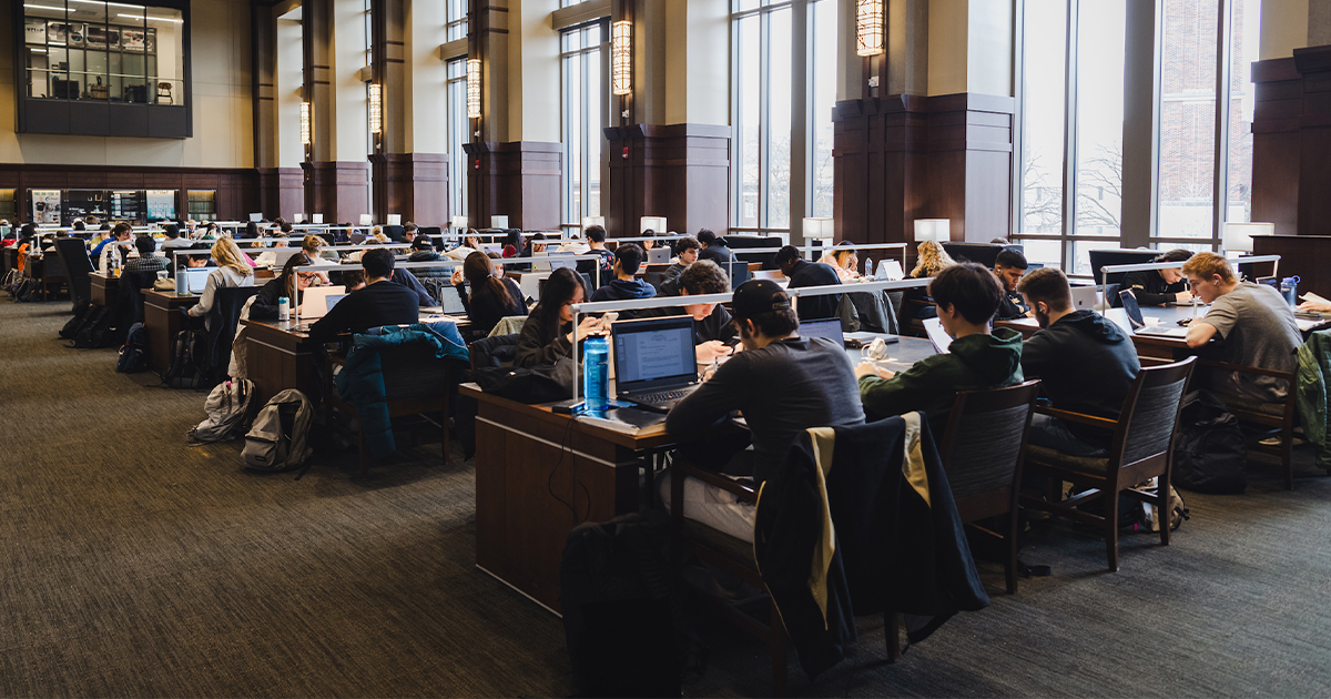 Purdue students seated, working on their laptops in a large hall.
