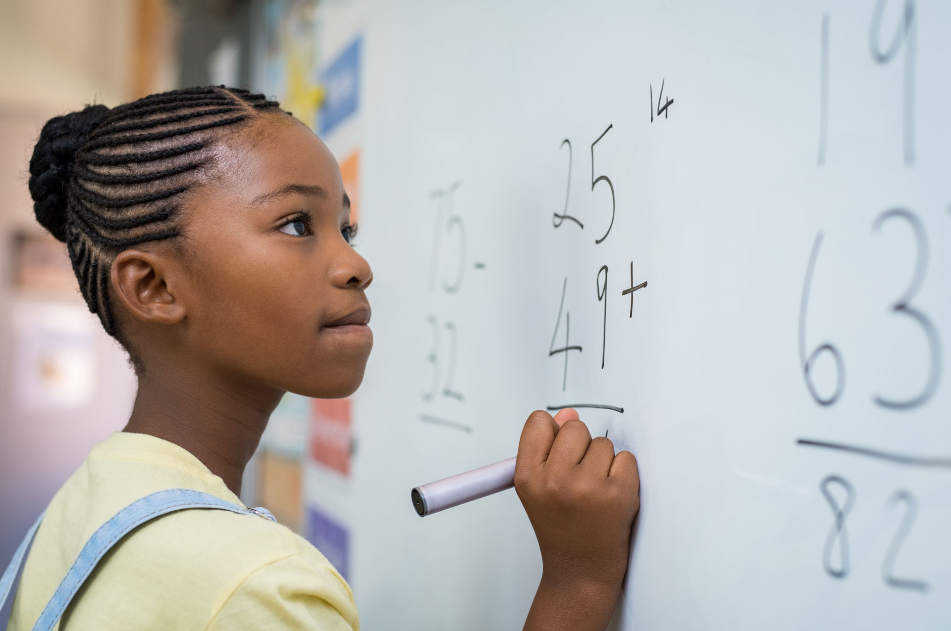 A black female student studies a math problem on a whiteboard. 