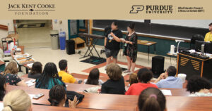 Two students speaking at the front of a lecture hall.