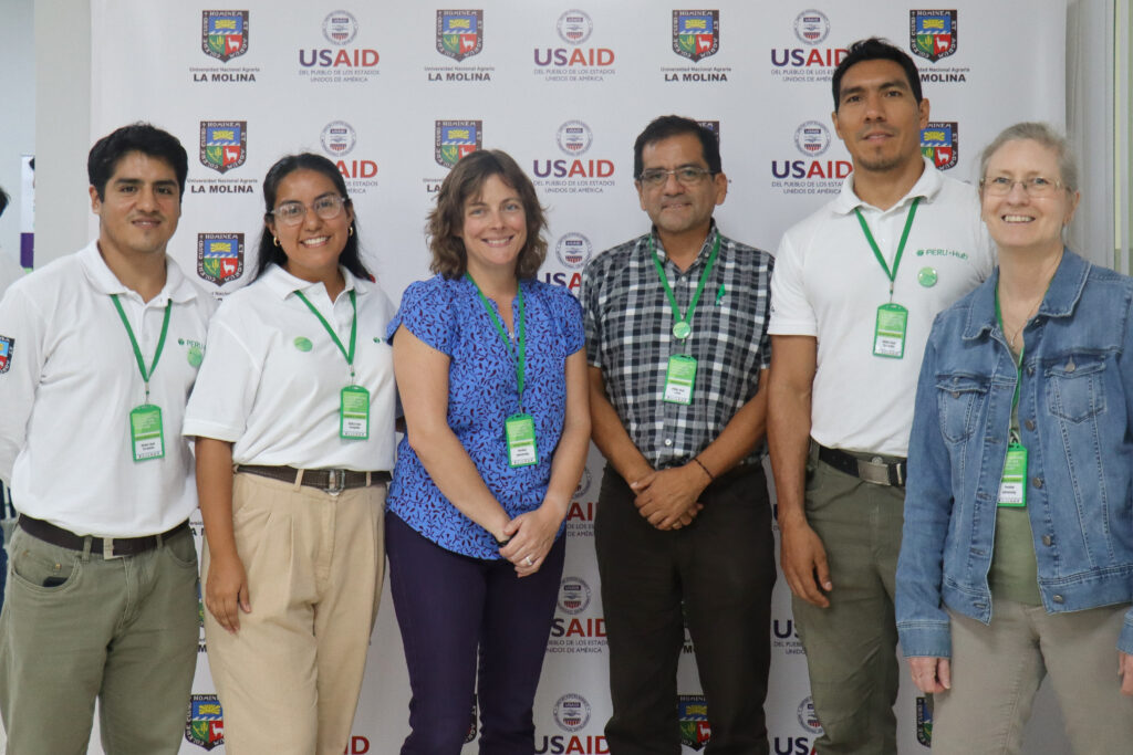The PERU-Hub Knowledge team standing in front of a USAID background. They are each wearing green PERU-Hub lanyards.