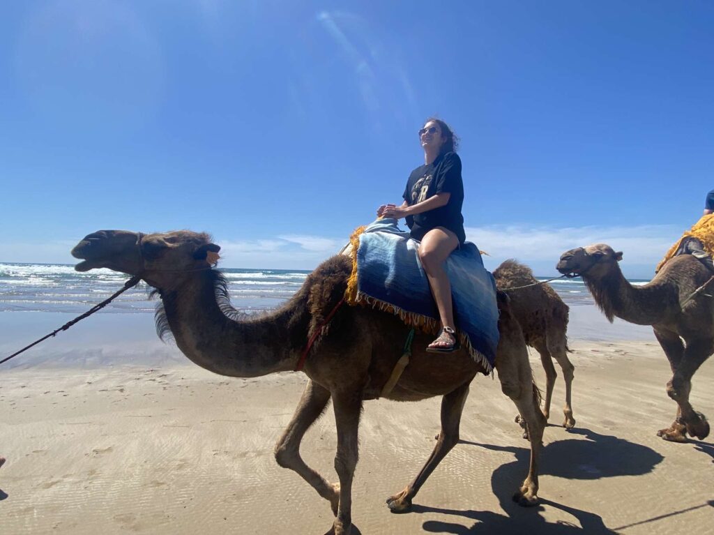 Paige Fulkerson riding a camel in a sandy area in Morocco
