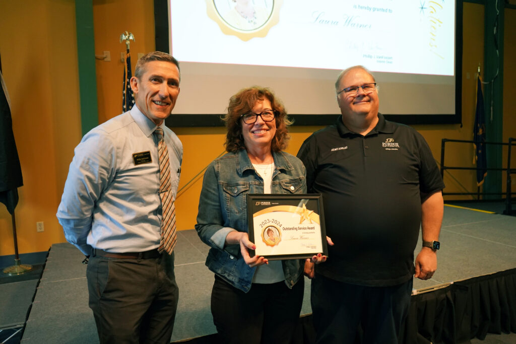 Laura Warner holding a certificate for the 2023-2024 Outstanding Service Award. Beside her are Interim Dean VanFossen and Wayne Wright