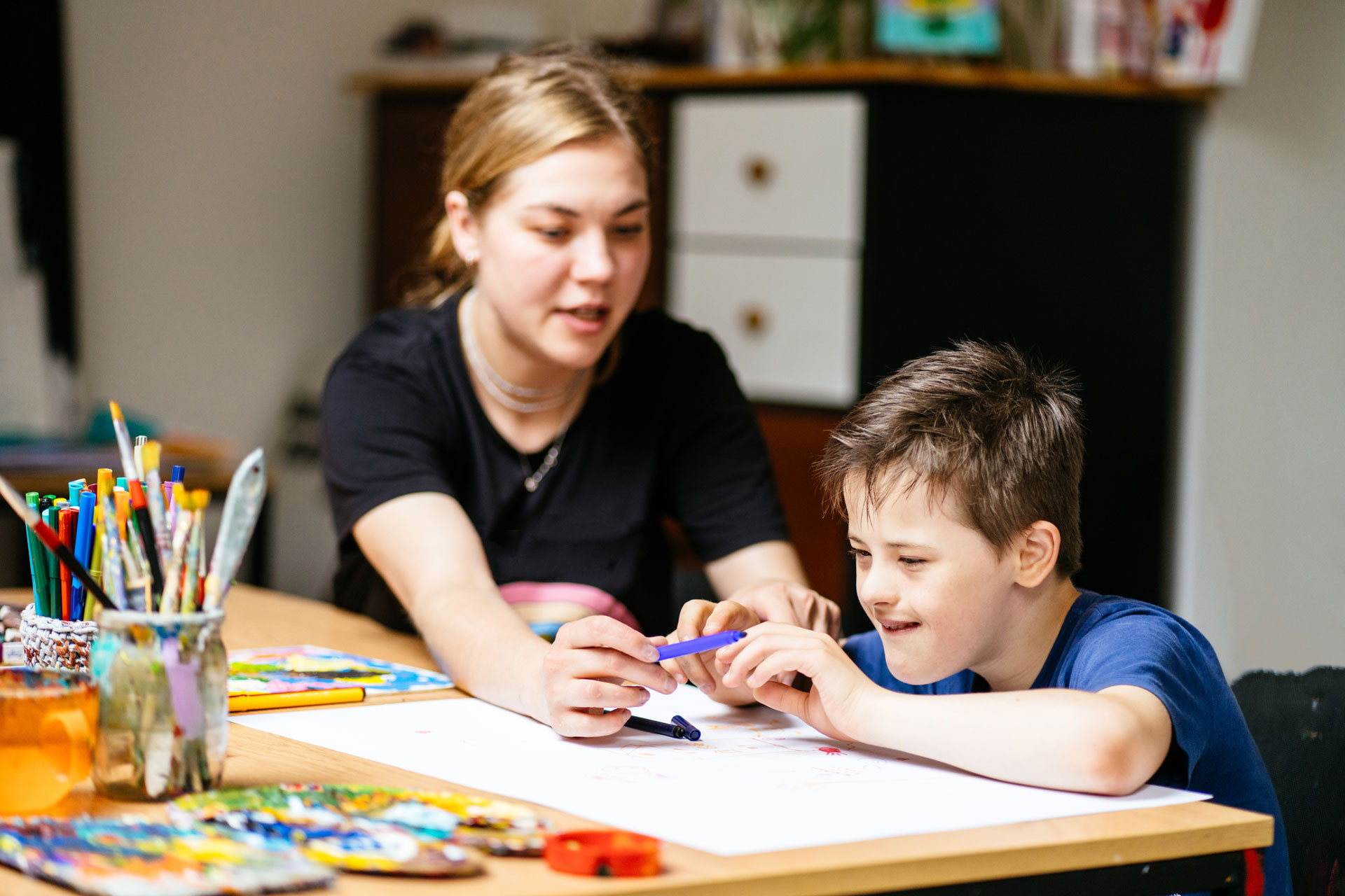 A female teacher works with a student with down syndrome.