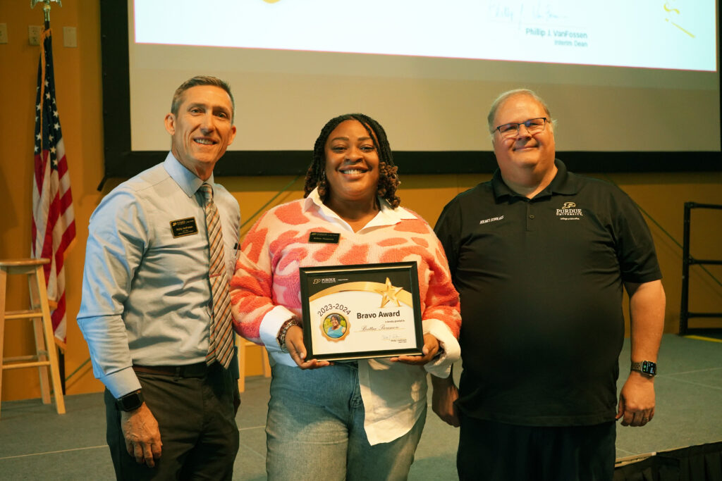Brittne Paramore holding a certificate for the 2023-2024 Bravo Award. Beside her are Interim Dean VanFossen and Wayne Wright