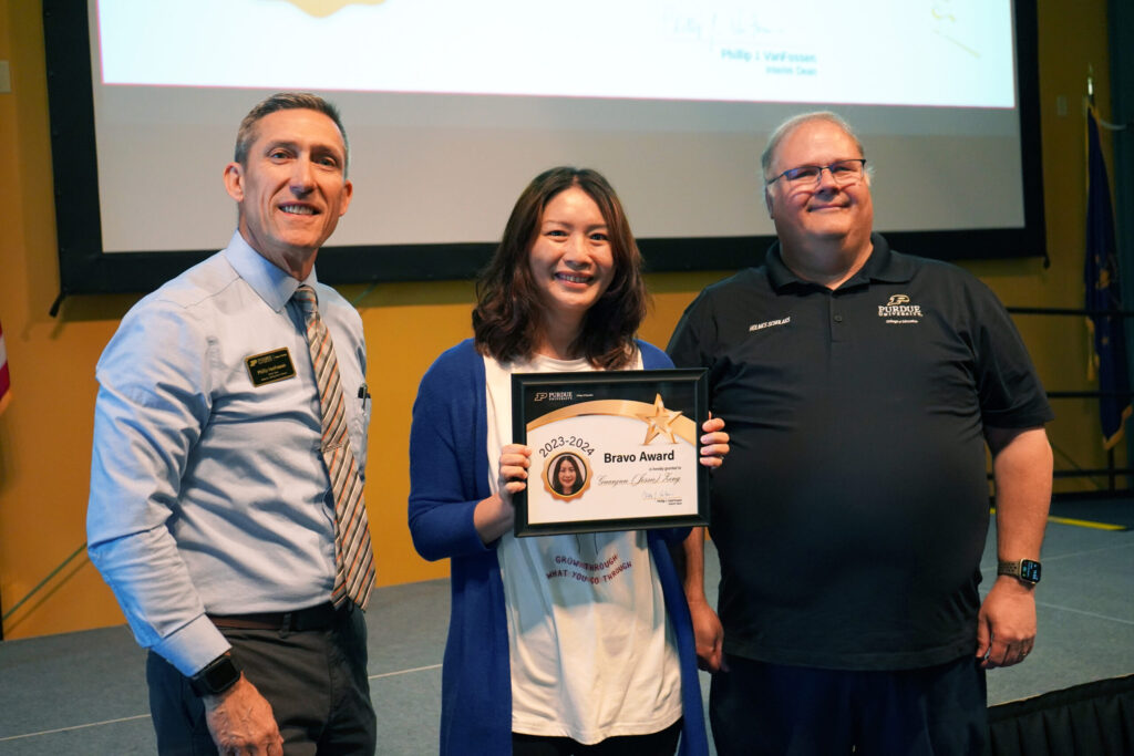 Jessie Zeng holding a certificate for the 2023-2024 Bravo Award. Beside her are Interim Dean VanFossen and Wayne Wright
