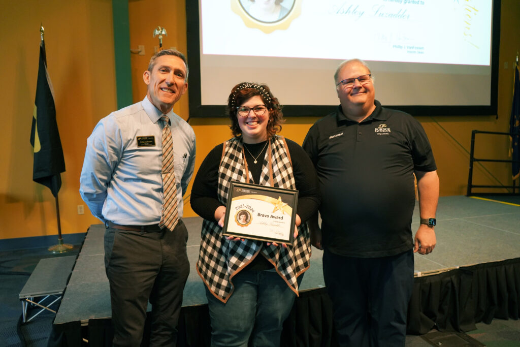 Ashley Luzadder holding a certificate for the 2023-2024 Bravo Award. Beside her are Interim Dean VanFossen and Wayne Wright