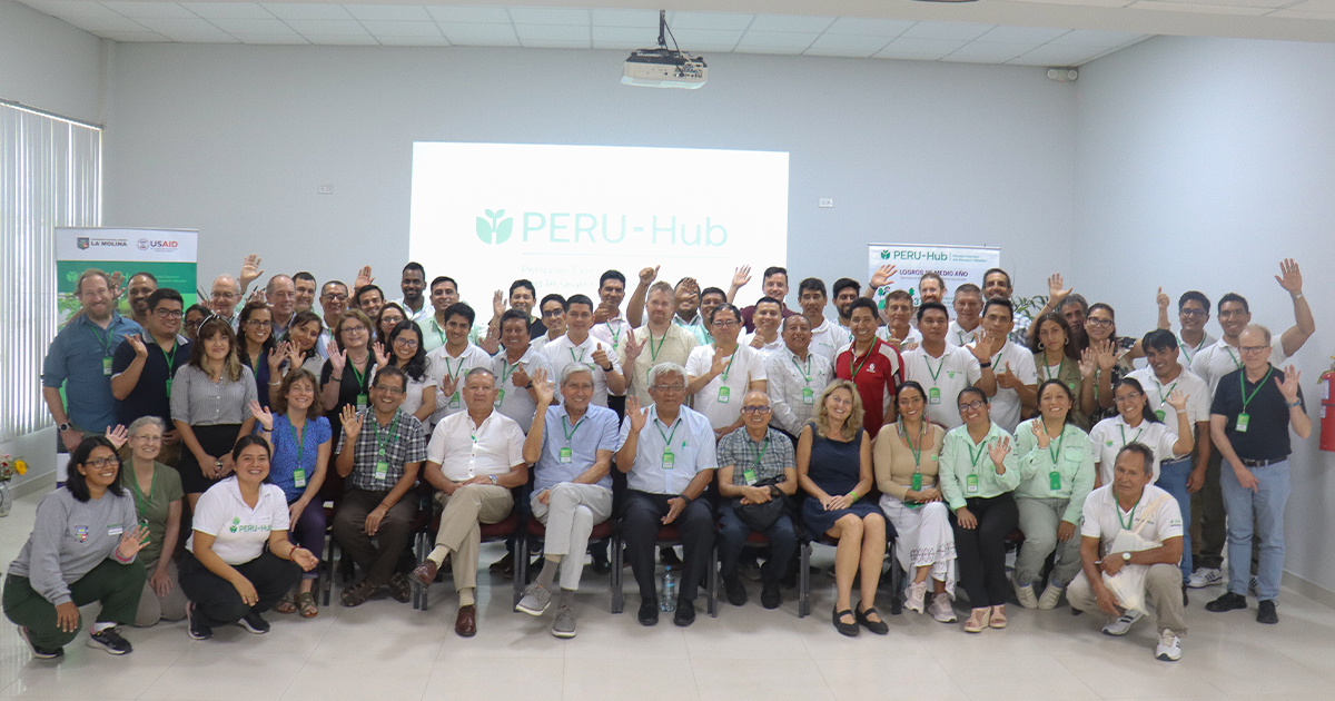 A large group of PERU-Hub staff and international partners smiling and waving.