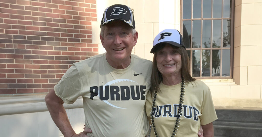 Kay and Jack Hayes standing in front of Purdue Campus wearing Purdue t-shirts.