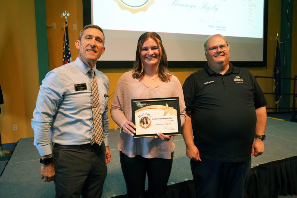 Bronwyn Rigsby holding a certificate for the Outstanding Undergraduate Sophomore Award. Beside her are Interim Dean VanFossen and Wayne Wright