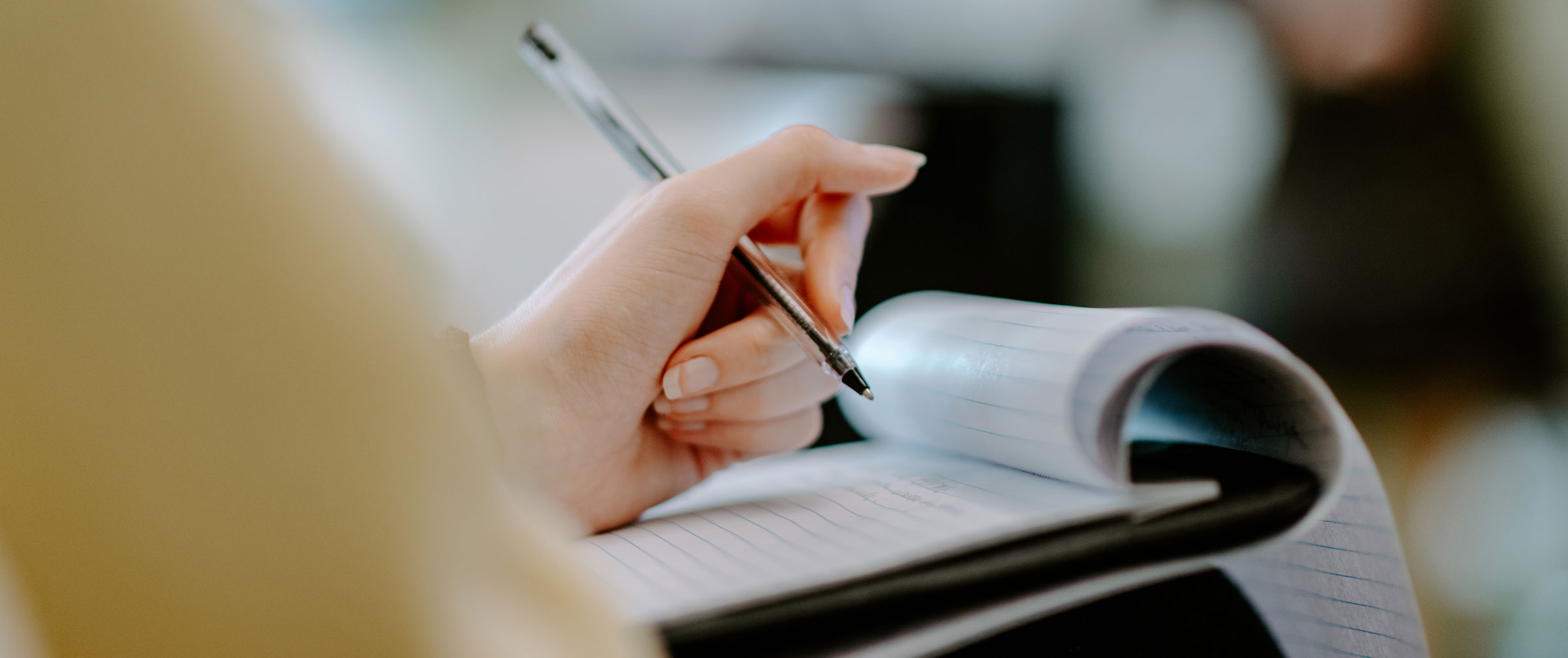 A white hand is shown writing in a legal notepad