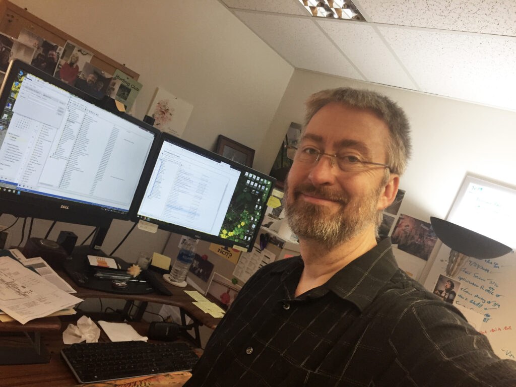 A selfie of Bob Evans working in front of a dual-monitor setup.