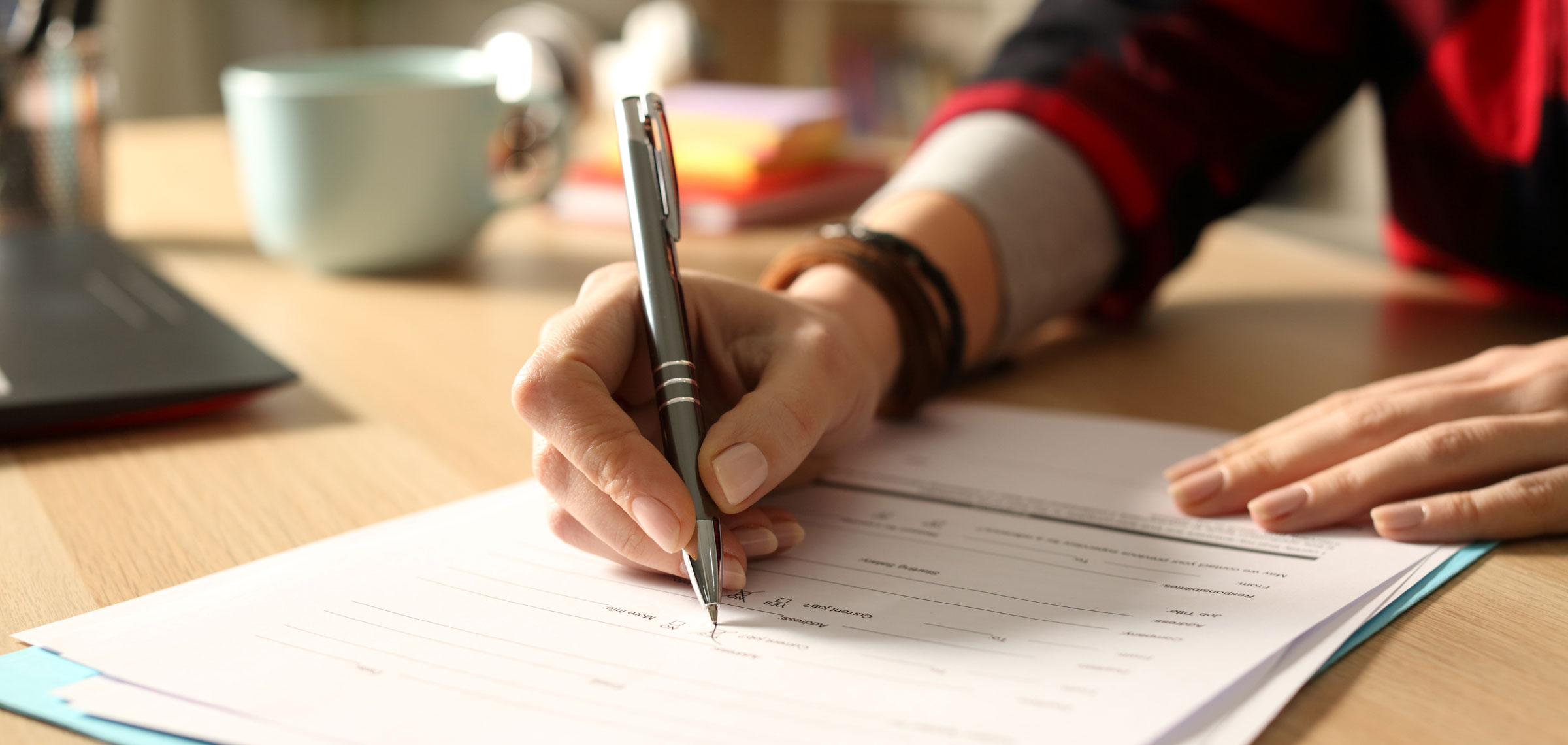 A white hand holds a pen as it marks on a form.