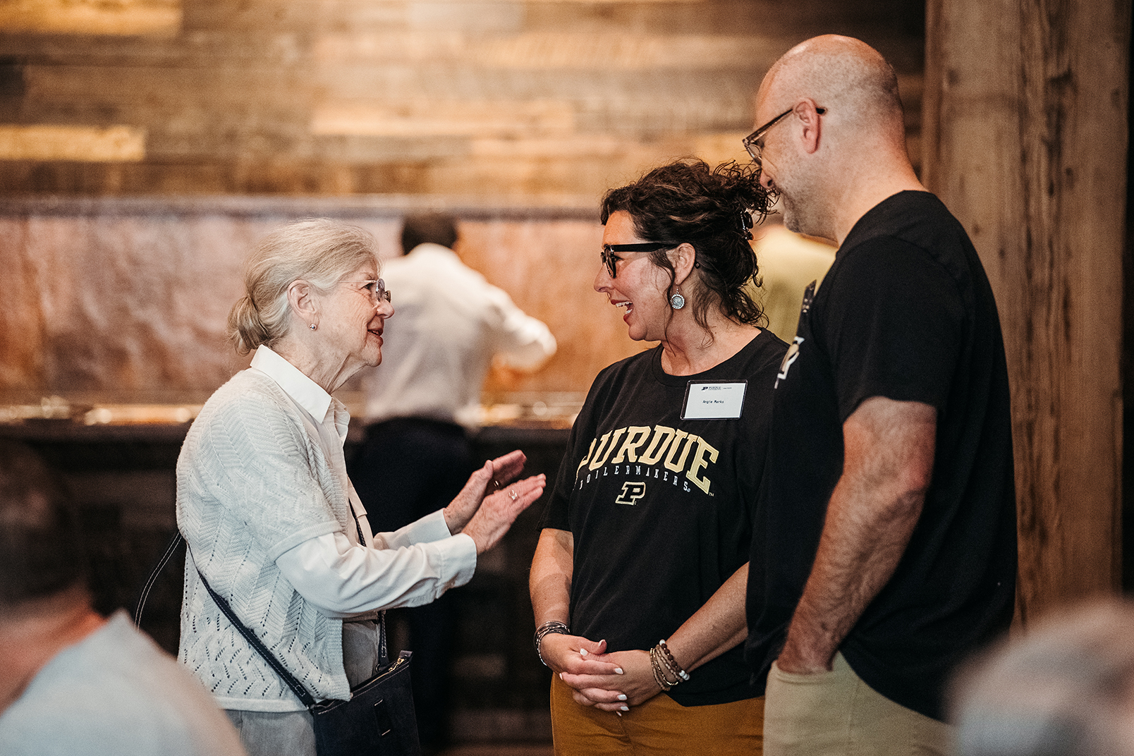 Three Education alumni having a conversation at an event.