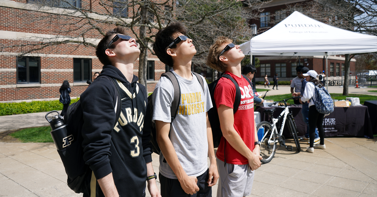 Three College of Education students viewing the solar eclipse through their solar glasses.