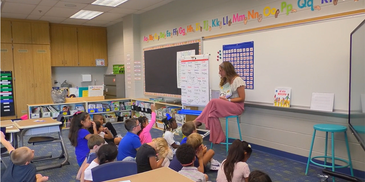 Teacher Ellie Grostefon reading a book to a group of schoolchildren.