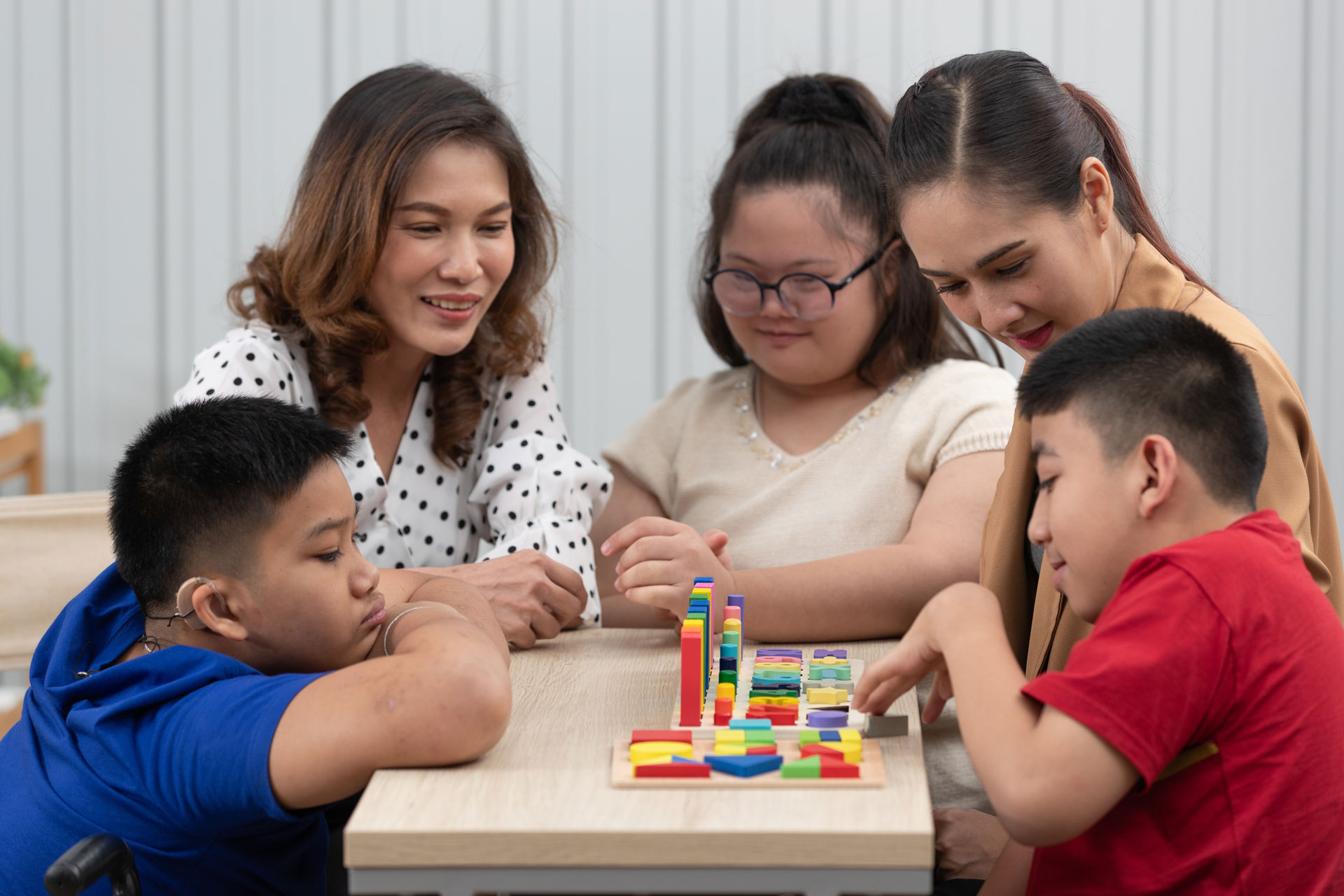 A female Asian teacher works with a group of special education students