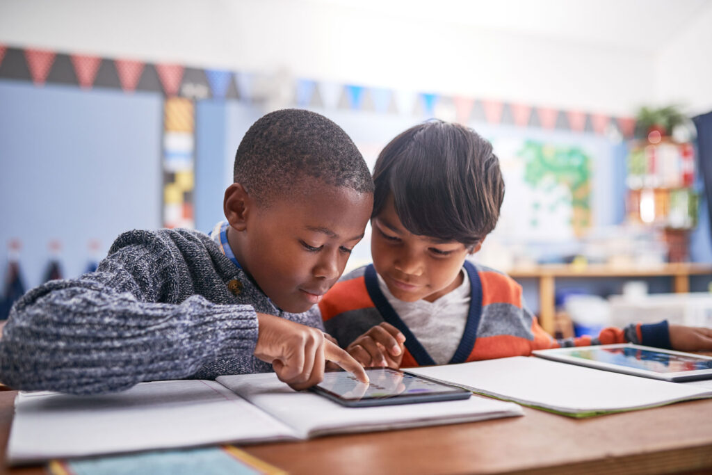 Two elementary school students look at an assignment on a tablet