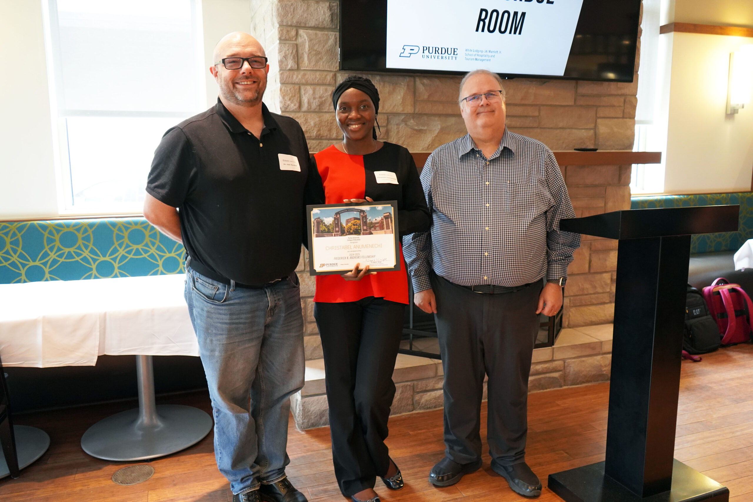 Christabel Anumenechi holding a certificate. Surrounding her are Dr. Jake Burdick and Wayne Wright.