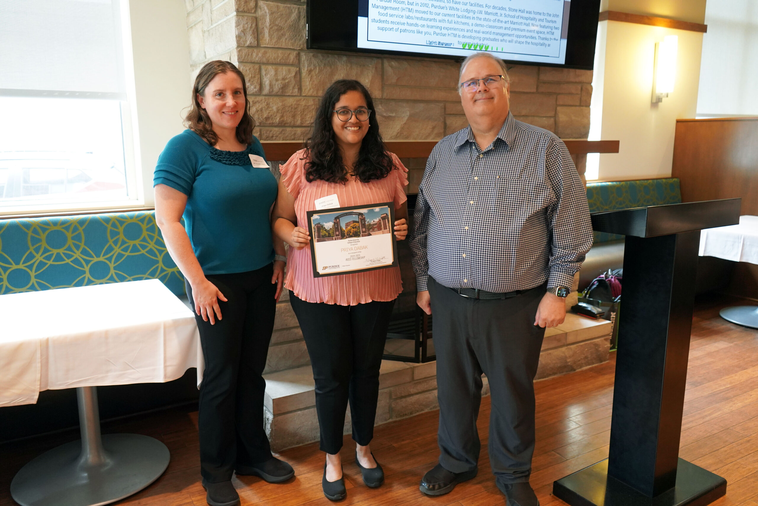 Priya Dabak holding a certificate. Surrounding her are Dr. Jennifer Renn and Dr. Wayne Wright.