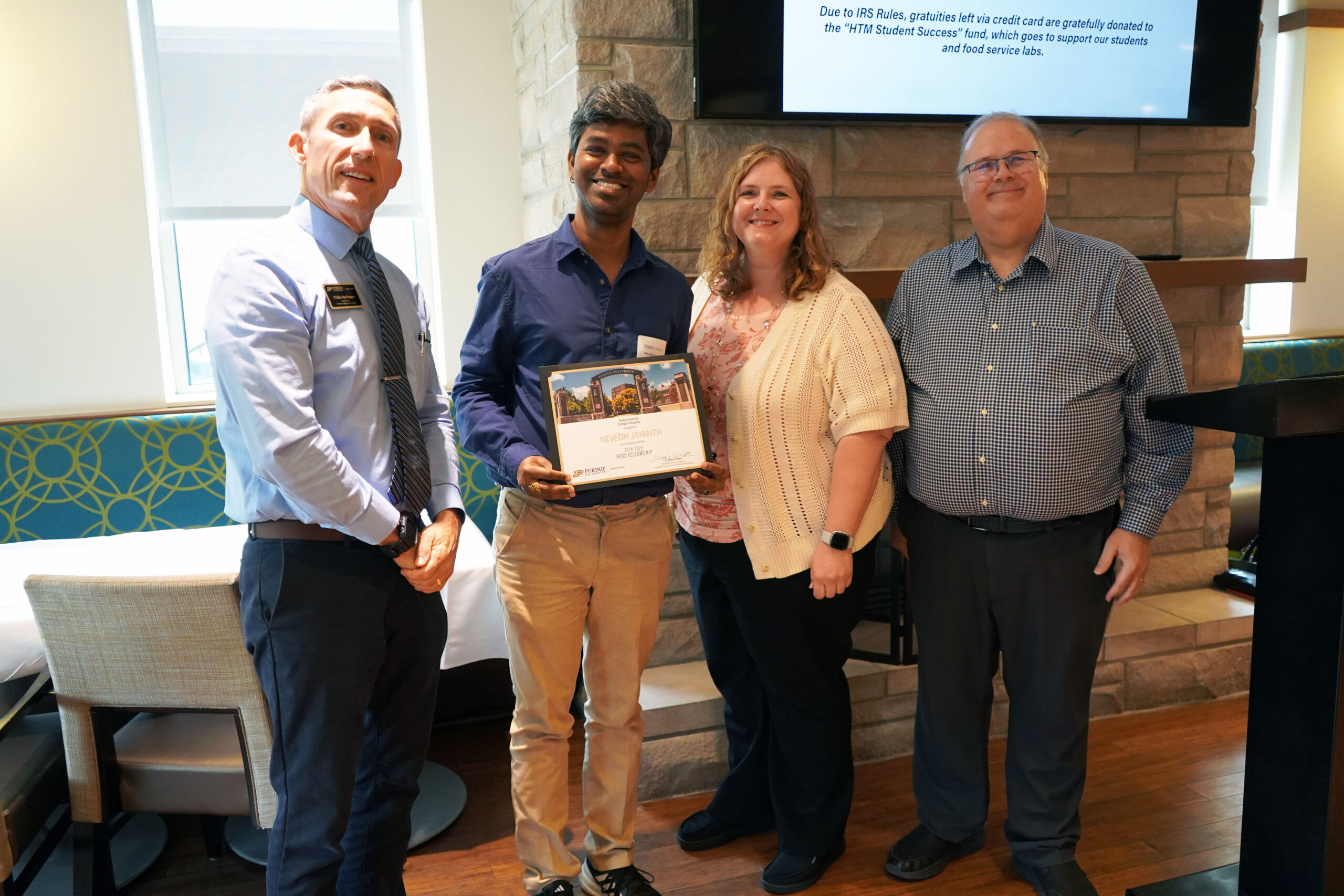 Nivedh Jayanth holding a certificate. Surrounding him are interim dean Phillip J. VanFossen, Dr. Rebekah Hammack, and Dr. Wayne Wright.