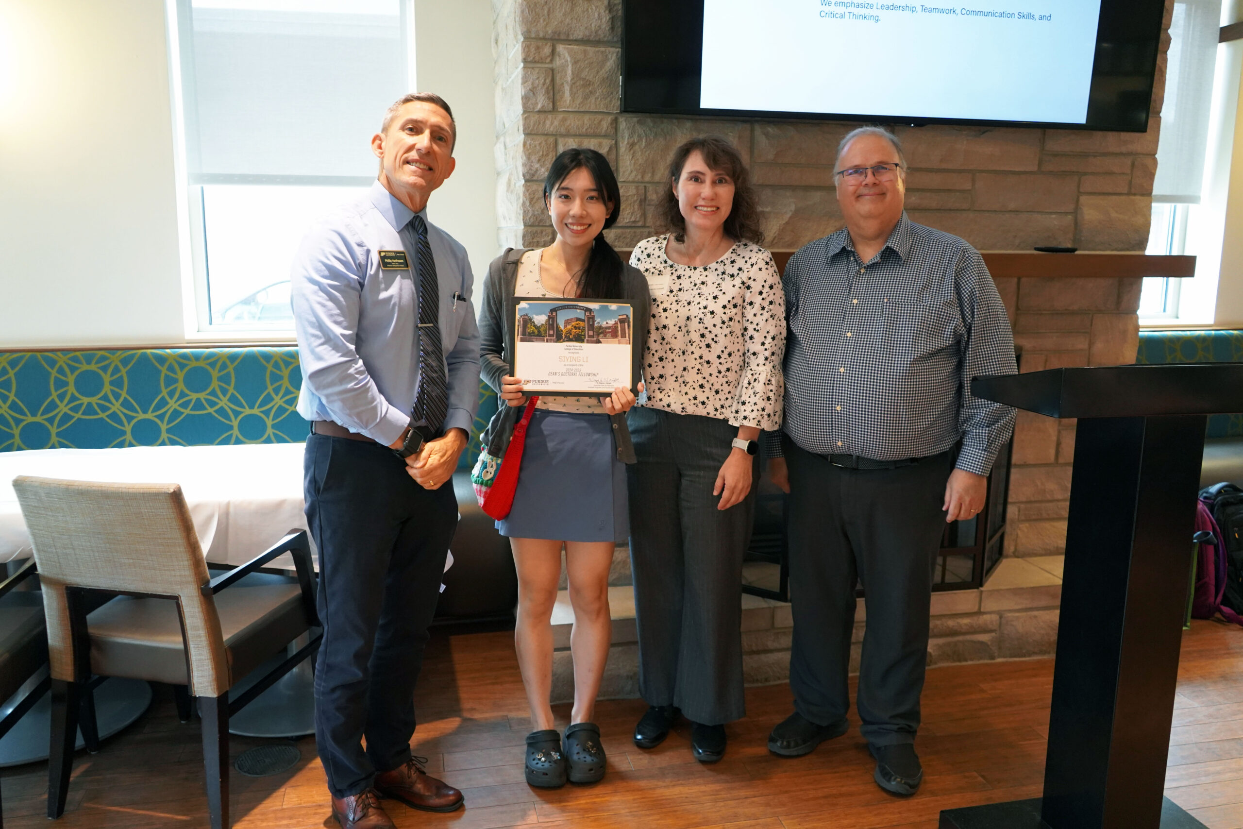 Siying Li holding a certificate. Surrounding her are interim dean Phillip J. VanFossen, Dr. Victoria Lowell, and Dr. Wayne Wright.