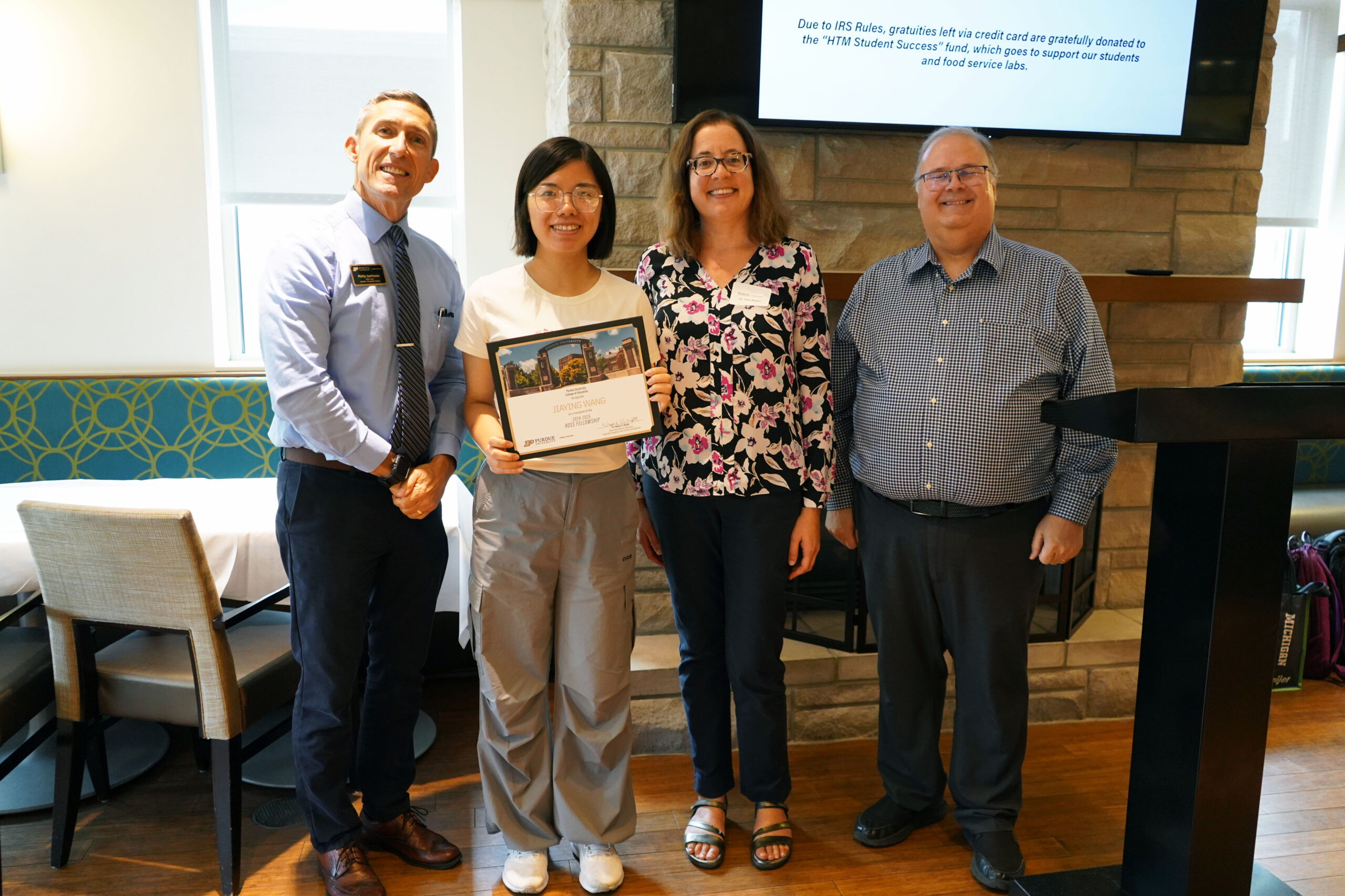 Jiayang Wang holding a certificate. Surrounding her are interim dean Phillip J. VanFossen, Dr. Toni Rogat, and Dr. Wayne Wright.