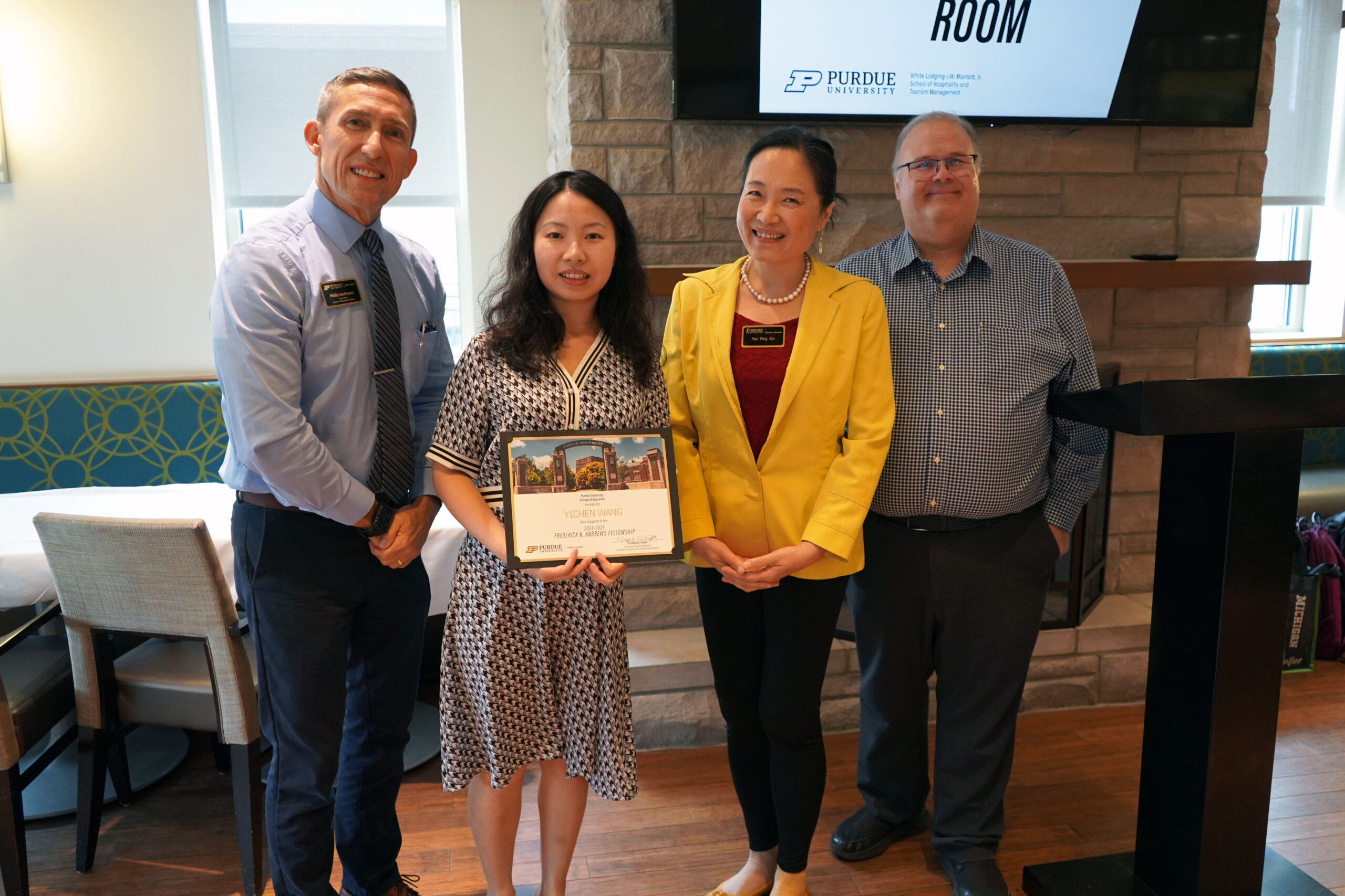 Yichen Wang holding a certificate. Surrounding her are interim dean Phillip J. VanFossen, Dr. Yan Ping Xin, and Dr. Wayne Wright.