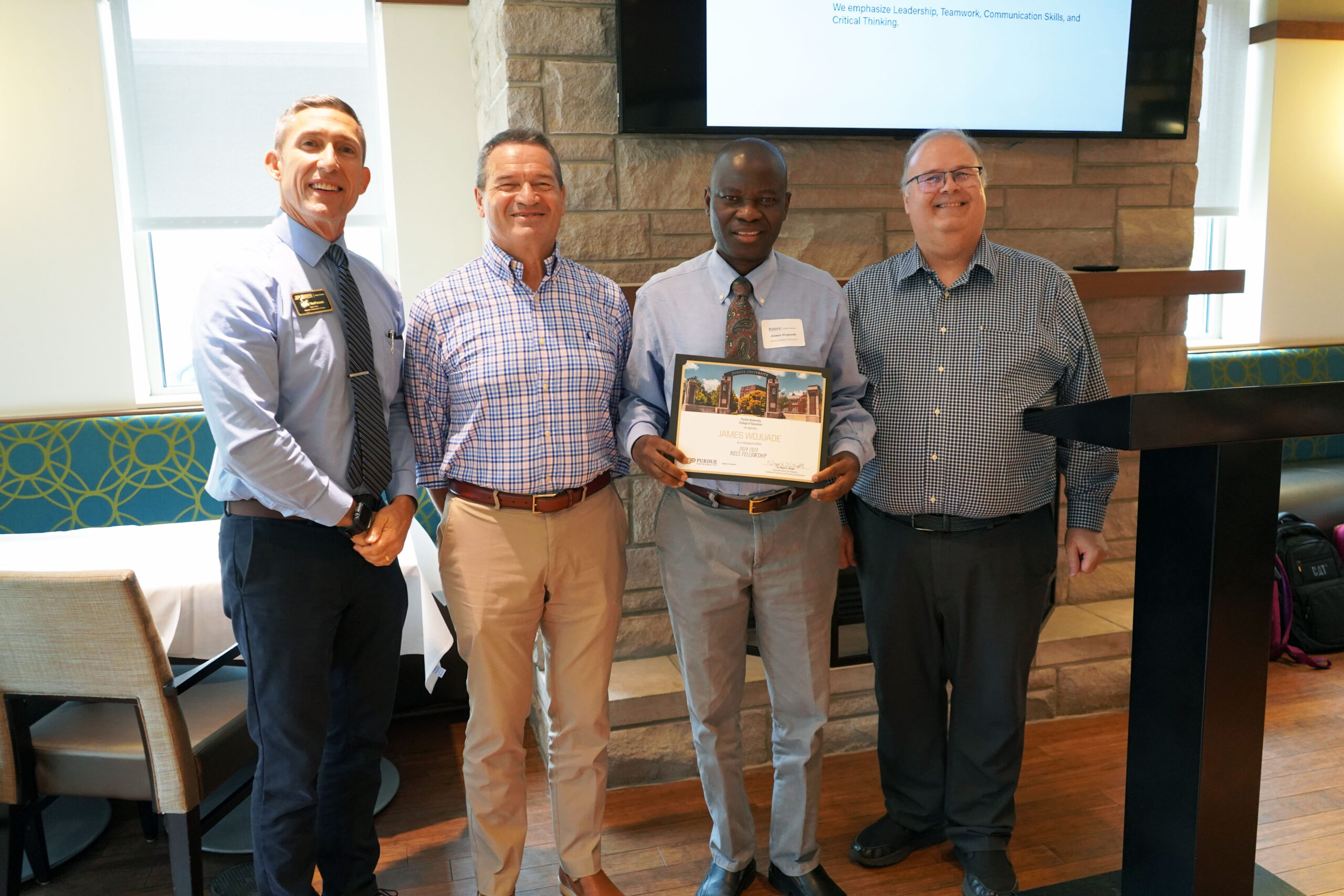 James Wojuade holding a certificate. Surrounding him are interim dean Phillip J. VanFossen, Dr. Anatoli Rapoport, and Dr. Wayne Wright.