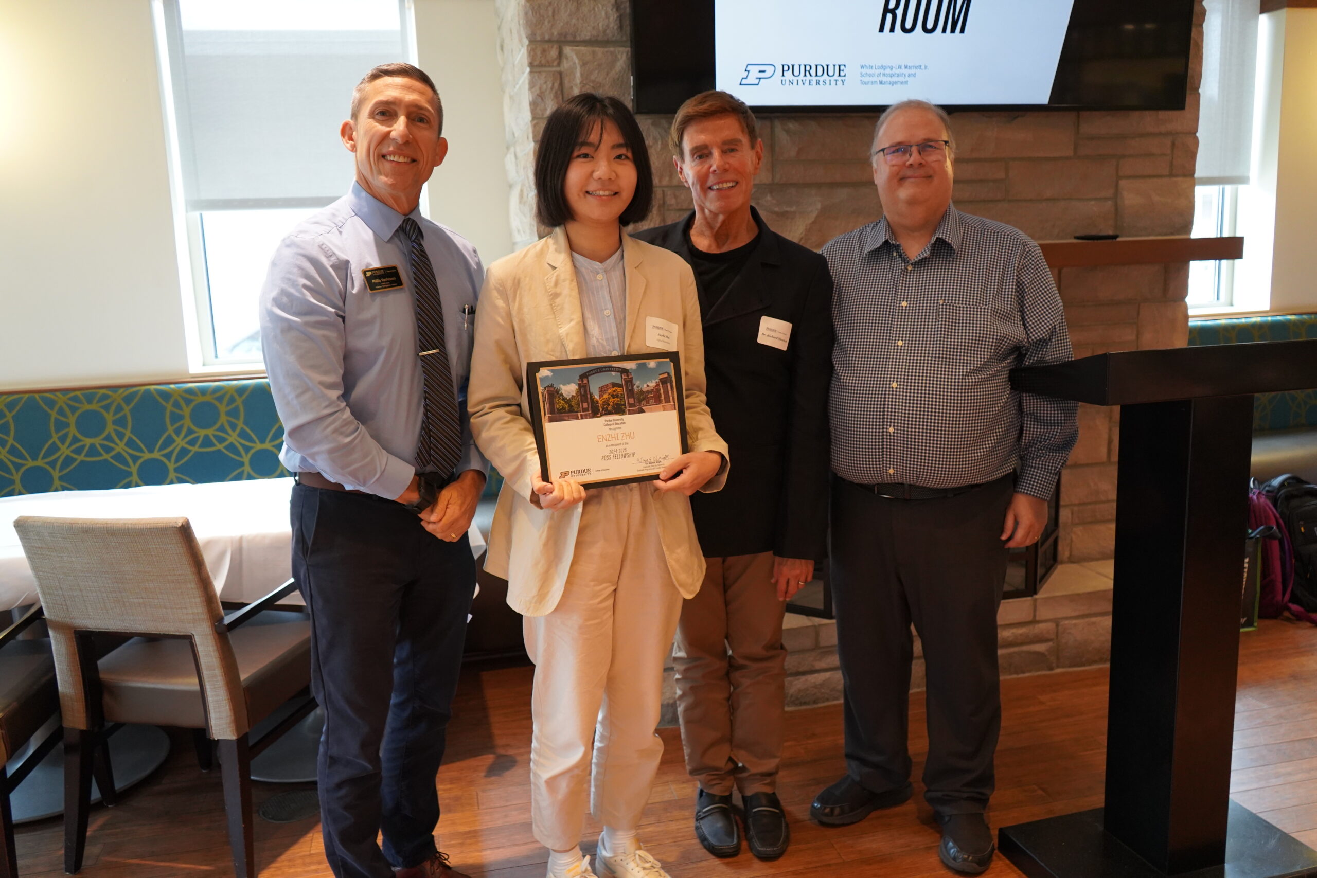 Enzhi Zhu holding a certificate. Surrounding her are interim dean Phillip J. VanFossen, Dr. F. Richard Olenchak, and Dr. Wayne Wright.