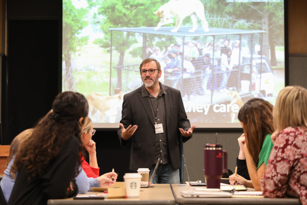 Judson Wright, standing in front of a projector screen speaking to a group of ICLCLE attendees.