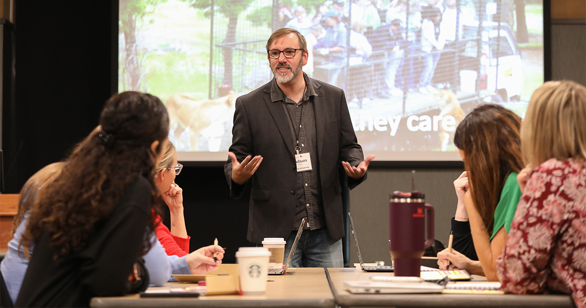 Judson Wright, standing in front of a projector screen speaking to a group of ICLCLE attendees.
