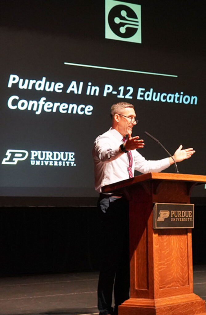 Phil VanFossen standing at a podium in front of a presentation titled, Purdue AI in P-12 Education Conference.