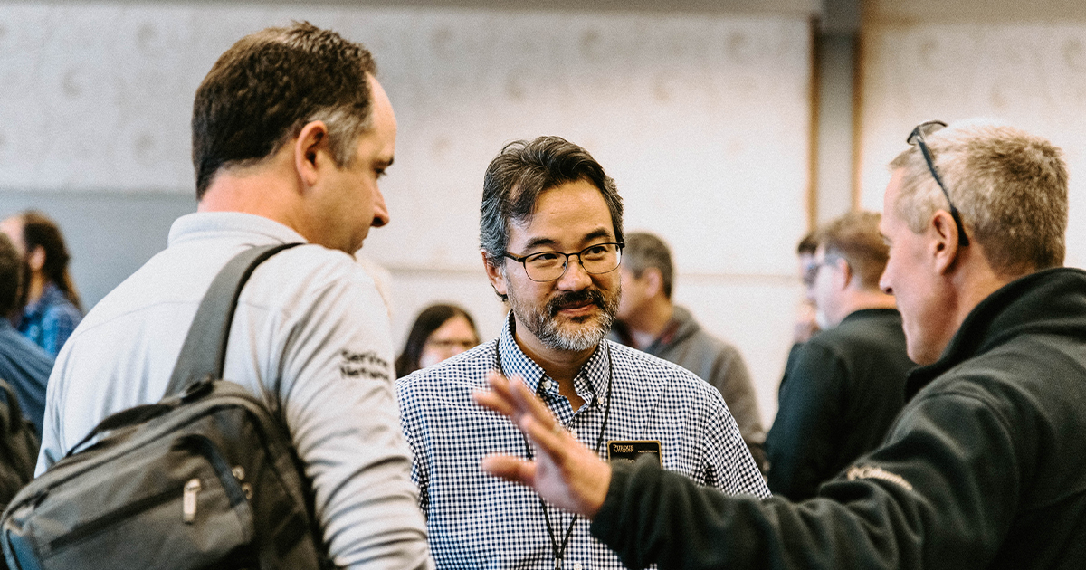 Bill Watson conversing with two conference attendees.