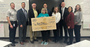 Diann Vernon holding a large check surrounded by Greater Lafayette Commerce members.