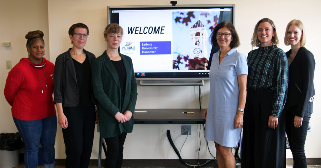Faculty from Purdue and Leibniz University Hannover's standing in front of a computer monitor. 